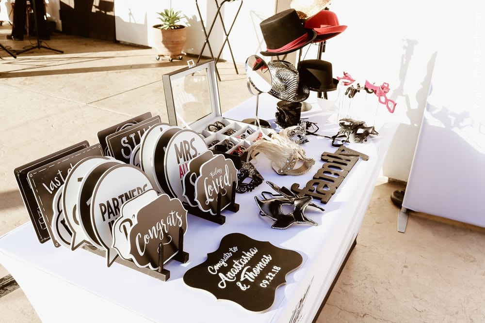 Photo booth props and signs for wedding celebration, featuring messages like "Congrats," "Partners," and "Mrs.," alongside hats and masks, highlighting the fun atmosphere at Anastasha and Thomas' wedding event.