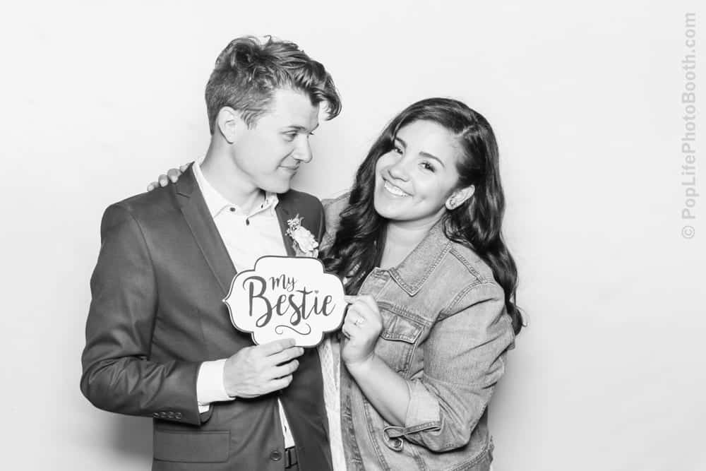 Couple posing in photo booth, holding sign "my Bestie," celebrating friendship at Thomas and Anastasha's wedding reception with Pop Life Photo Booth.