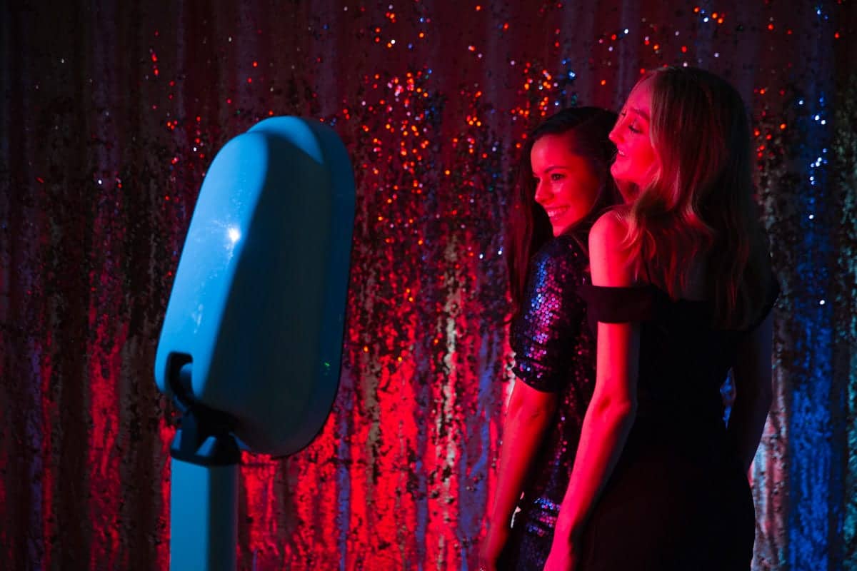 Girls enjoying a fun moment at a stylish Party Booth with colorful lighting, capturing memories at an event.