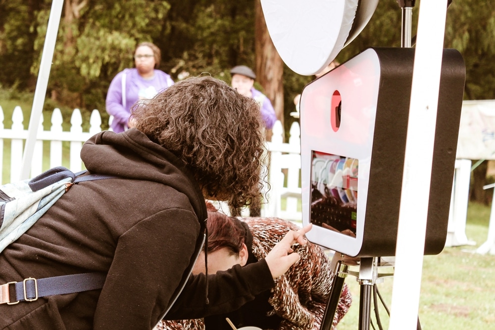Person interacting with a photo booth at the San Francisco AIDS Walk, showcasing team spirit and fun atmosphere in a fundraising event setting.