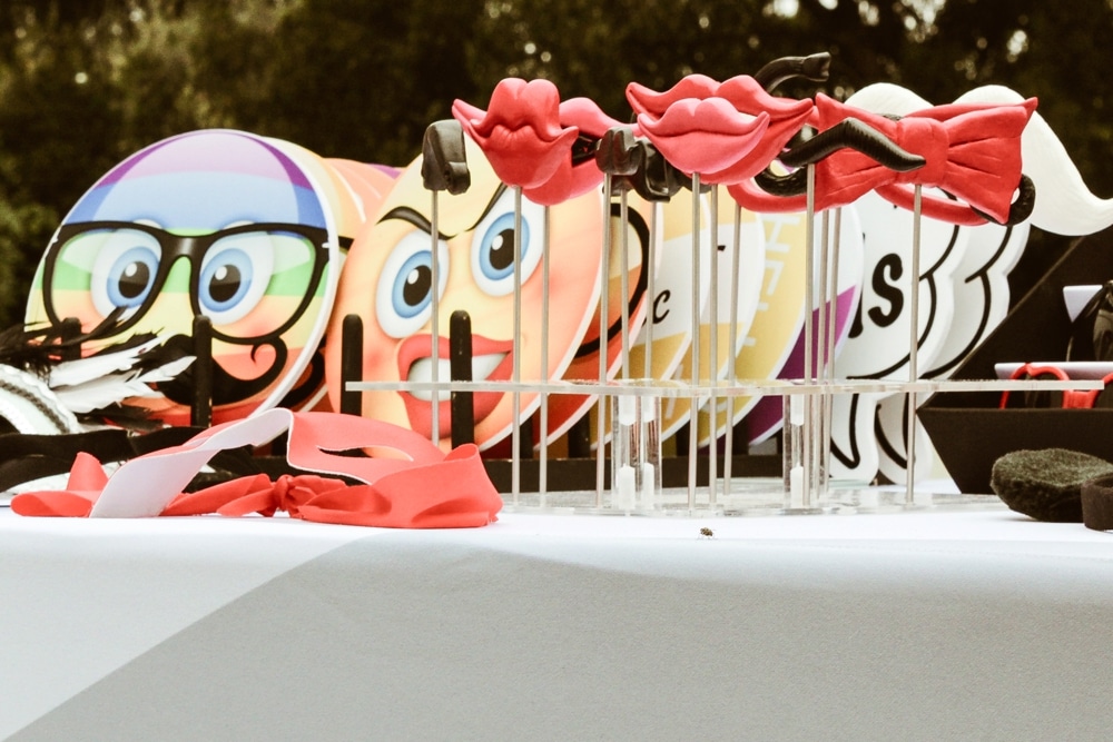 Colorful emoji props and playful red lip and mustache photo booth accessories on a table, enhancing the fun atmosphere of the San Francisco AIDS Walk fundraising event.