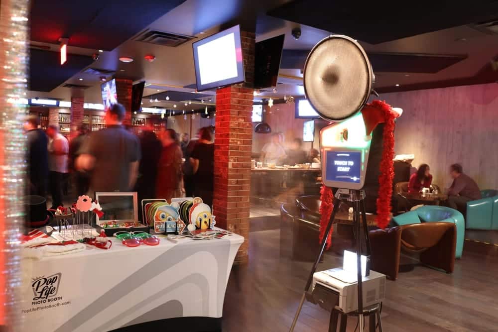 Pop Life Photo Booth setup featuring a photo booth station with props, inviting guests to capture memories at an event, surrounded by a lively atmosphere.