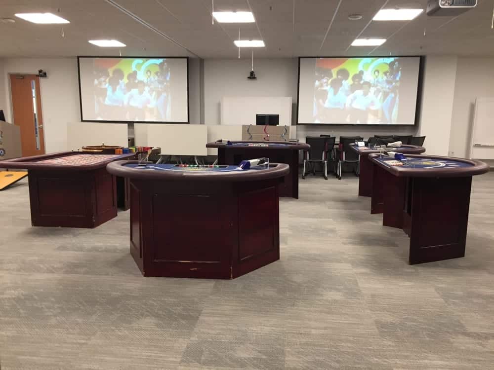 Event venue setup with multiple gaming tables and a projector screen displaying a vibrant image, illustrating an engaging atmosphere for celebrations and parties.