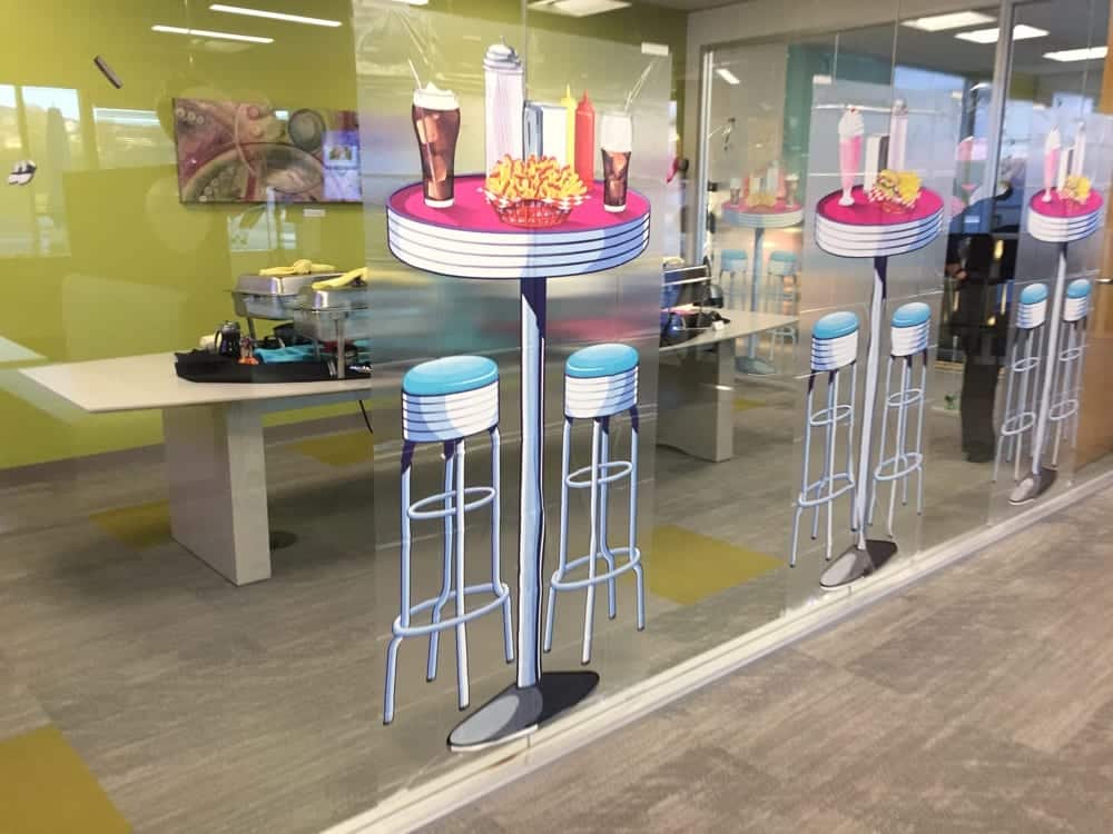 Colorful diner-style tables and stools with food items, enhancing event ambiance for photo booth experiences.