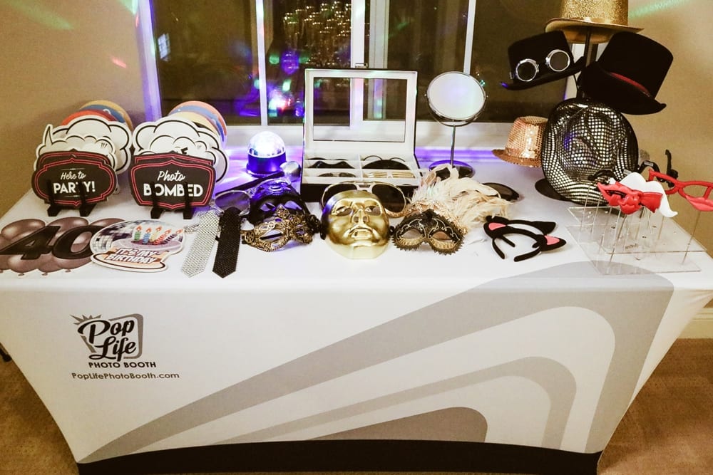 Photo booth setup featuring fun props like hats, masks, and signs saying "Photo Bombed" and "Let's Party!" for a casino-themed corporate event by Pop Life Photo Booth.