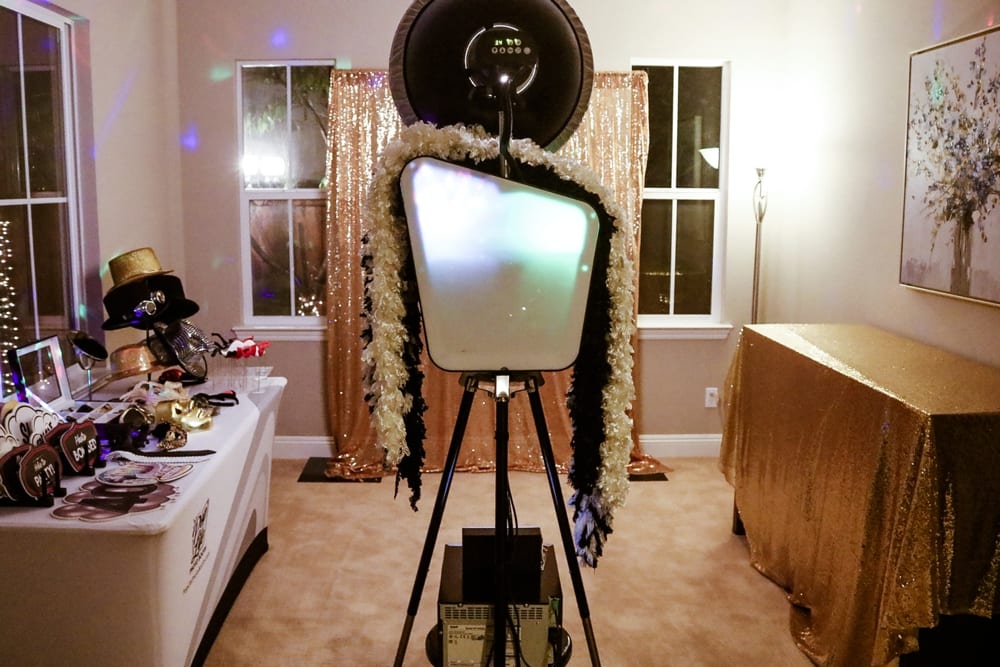 Photo booth setup with a backdrop of golden sequins, decorative hats, and props for a casino-themed party, emphasizing a fun and festive atmosphere for corporate events.