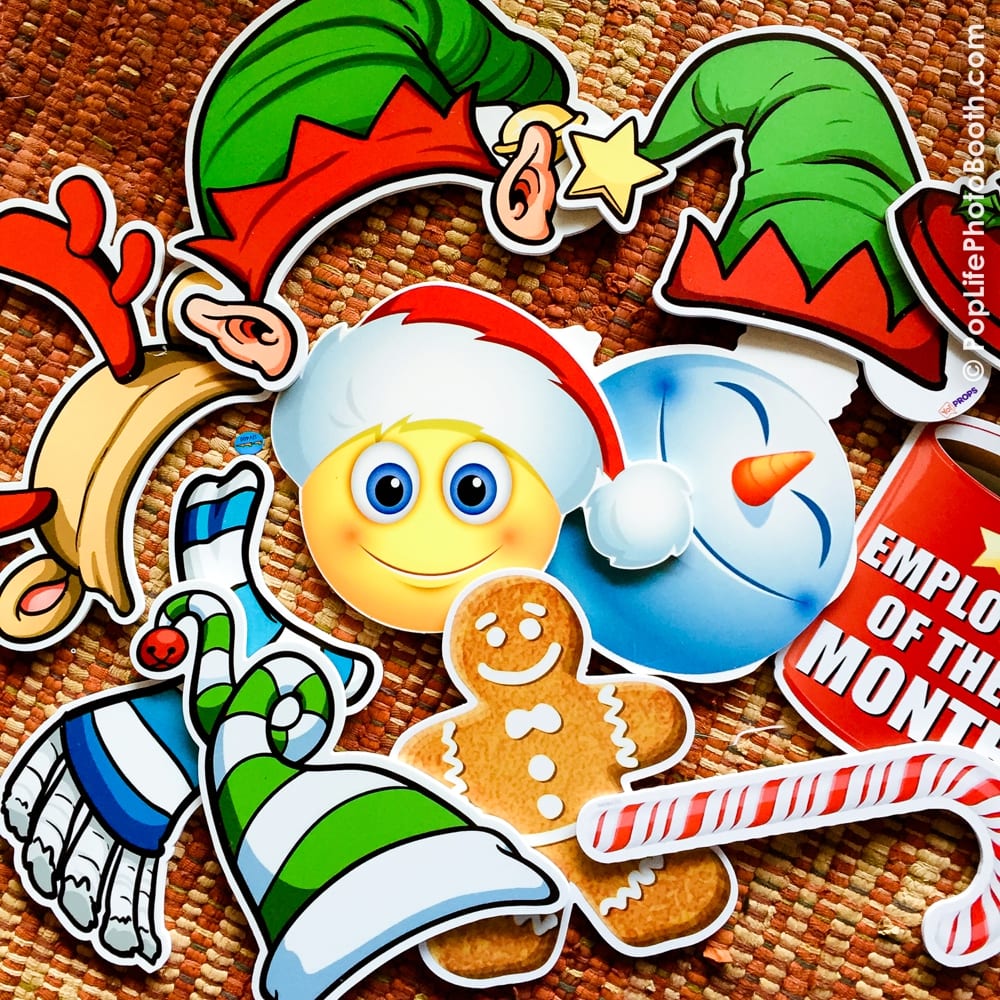 Colorful holiday-themed photo booth props including elf hats, a snowman, a smiling emoji, a gingerbread man, and candy canes, ideal for festive company parties.