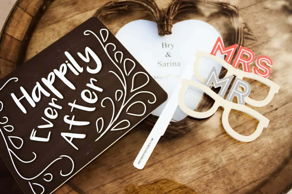 Happily Ever After sign with wedding date, decorative heart, and playful photo booth props labeled "Mr" and "Mrs" for wedding celebration.