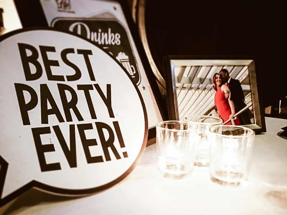 Best party ever sign with candles and framed photo of a couple celebrating, emphasizing joyful wedding atmosphere and memorable moments.