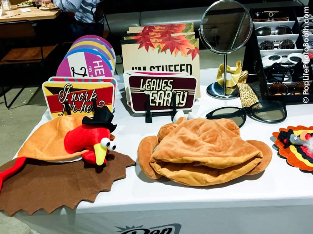 Thanksgiving-themed photo booth props including a turkey hat, festive signs, and sunglasses on a table at a corporate event hosted by Yelp.