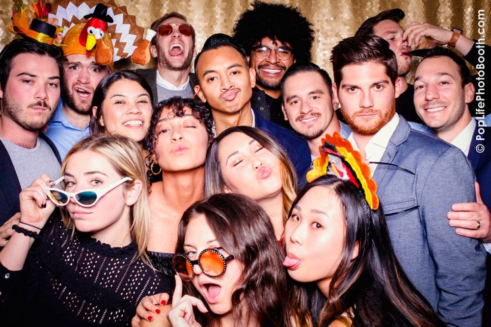 Group of guests at a Thanksgiving-themed photo booth, wearing festive props like turkey hats and sunglasses, celebrating together during a corporate event hosted by Yelp.