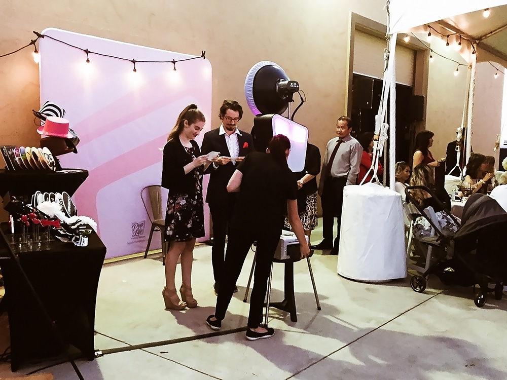 Photo booth setup at McGrail Vineyard event, featuring guests interacting, props displayed, and festive ambiance with string lights.