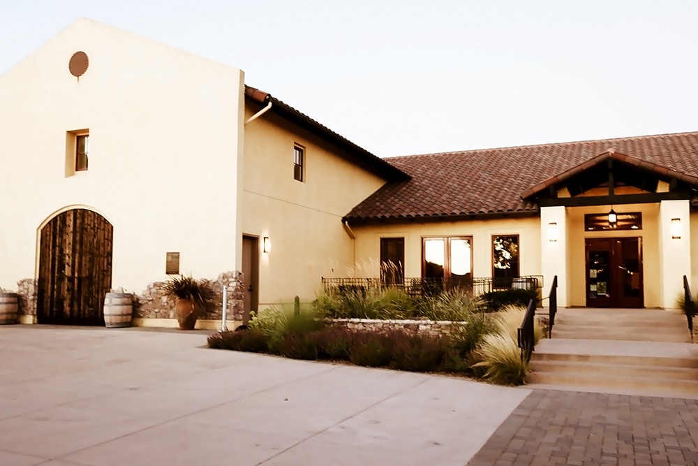 Beautiful front entrance of Las Positas Vineyard in Livermore, featuring rustic wooden doors, stone accents, and landscaped surroundings, ideal for event photography and gatherings.