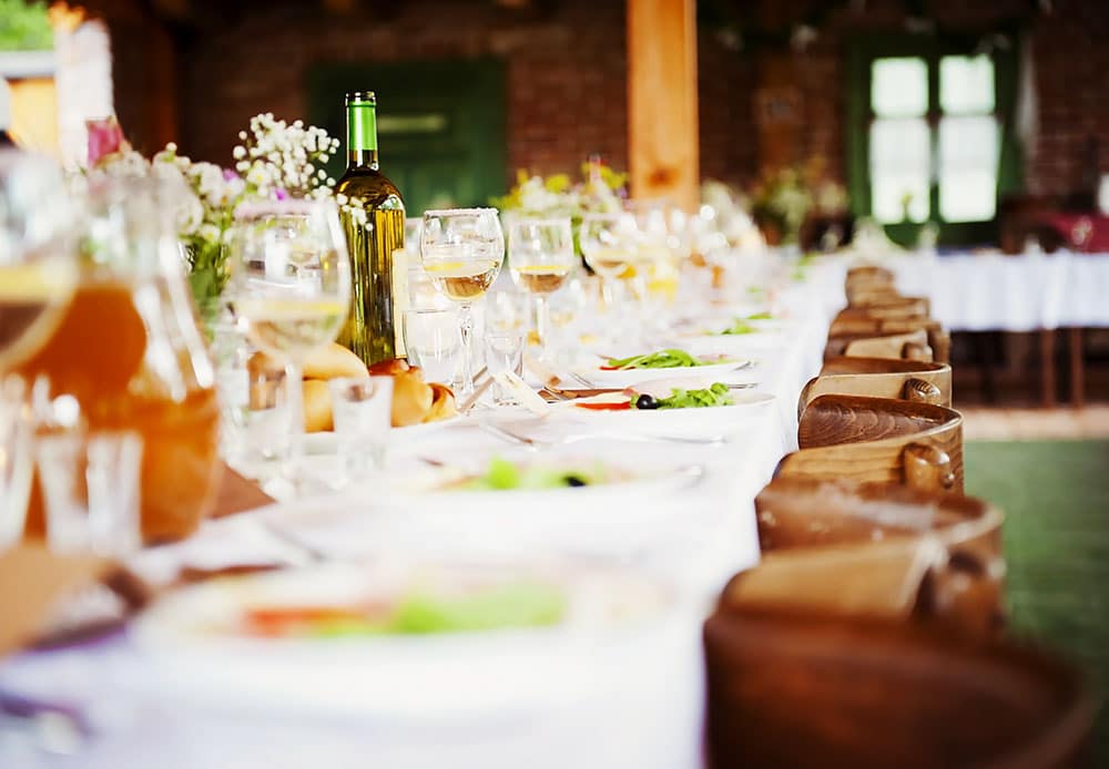 Elegant holiday party table setting with wine bottles, glasses, and plates of food, showcasing a festive atmosphere for corporate celebrations.