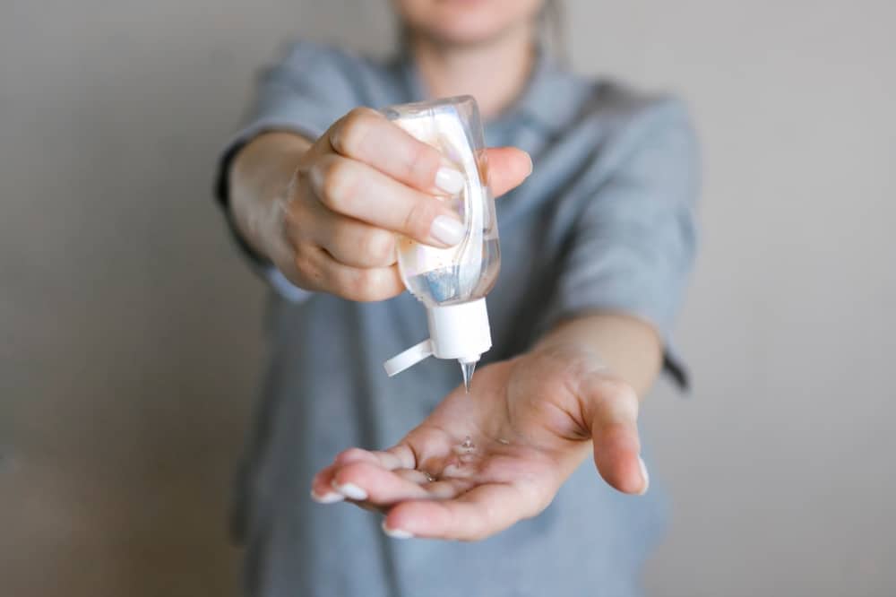 Person dispensing hand sanitizer from a bottle, emphasizing hygiene practices for safe events during the COVID-19 pandemic.