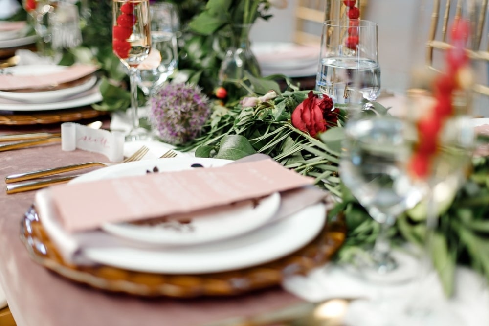Elegant wedding table setting featuring floral arrangements, pink menu cards, and decorative glassware, ideal for event planning and venue selection.