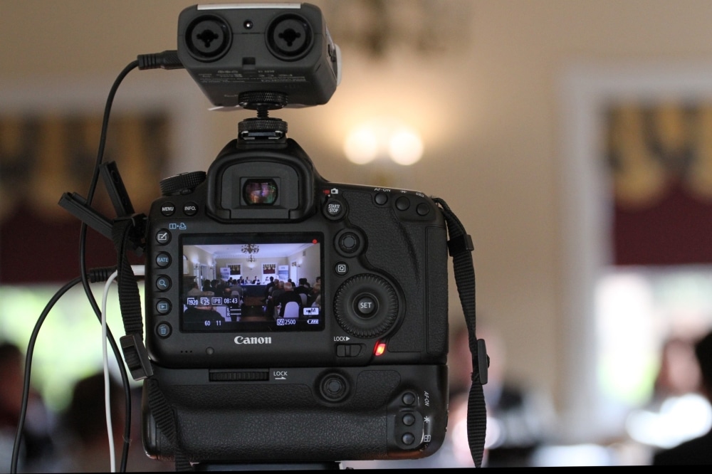 Professional camera capturing a wedding event with visible settings, highlighting the importance of hiring a qualified photographer for special occasions.