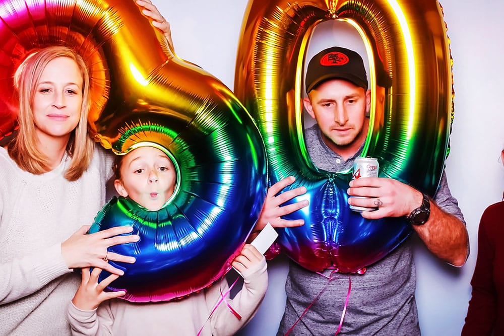 Family celebrating with colorful number balloons in a photo booth, emphasizing fun and memorable moments at private events.