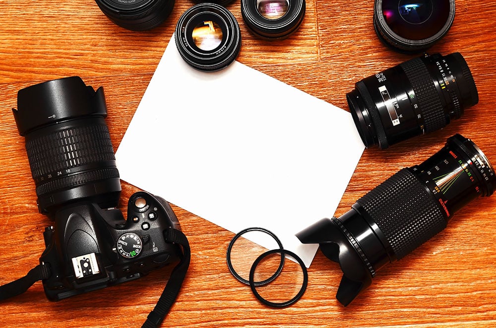 Complete kit for modern digital SLR camera with multiple lenses and blank sheet, illustrating photography equipment for event photography and photo booth rentals.