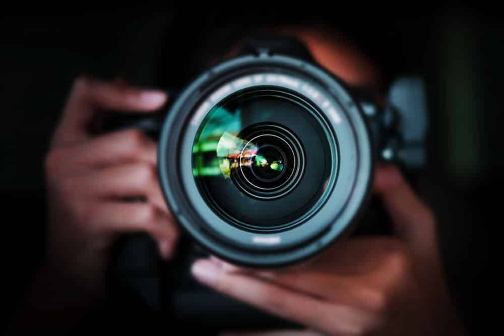 Photographer holding a camera with a visible lens, emphasizing photography skills relevant for event photography and client inquiries.