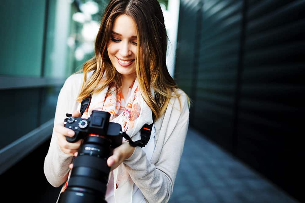 Professional photographer smiling while holding a DSLR camera, showcasing expertise in event photography.