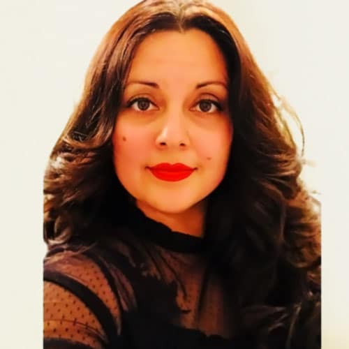 Tasha Singh, professional event planner and designer, showcasing elegant style with glamorous makeup and a black attire, reflecting winter wedding trends and festive color schemes.
