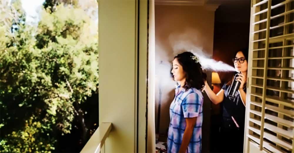 Bride getting hairstyling with hair spray during bridal trial run, showcasing preparation for wedding day look.