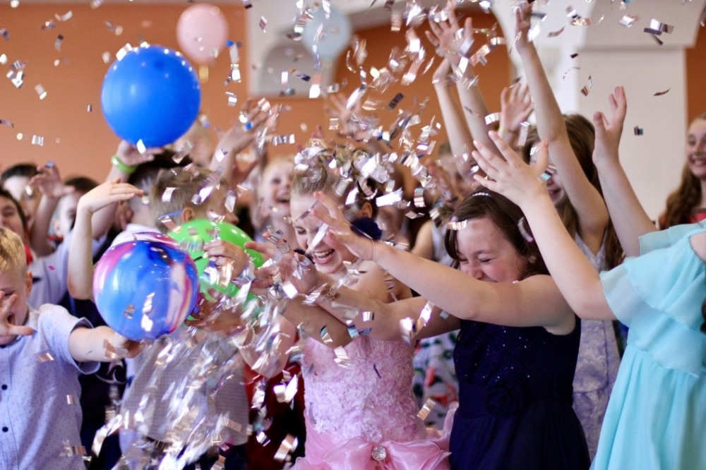 Kids celebrating at a party, throwing colorful balloons and shiny confetti, embodying joy and togetherness in a festive atmosphere.