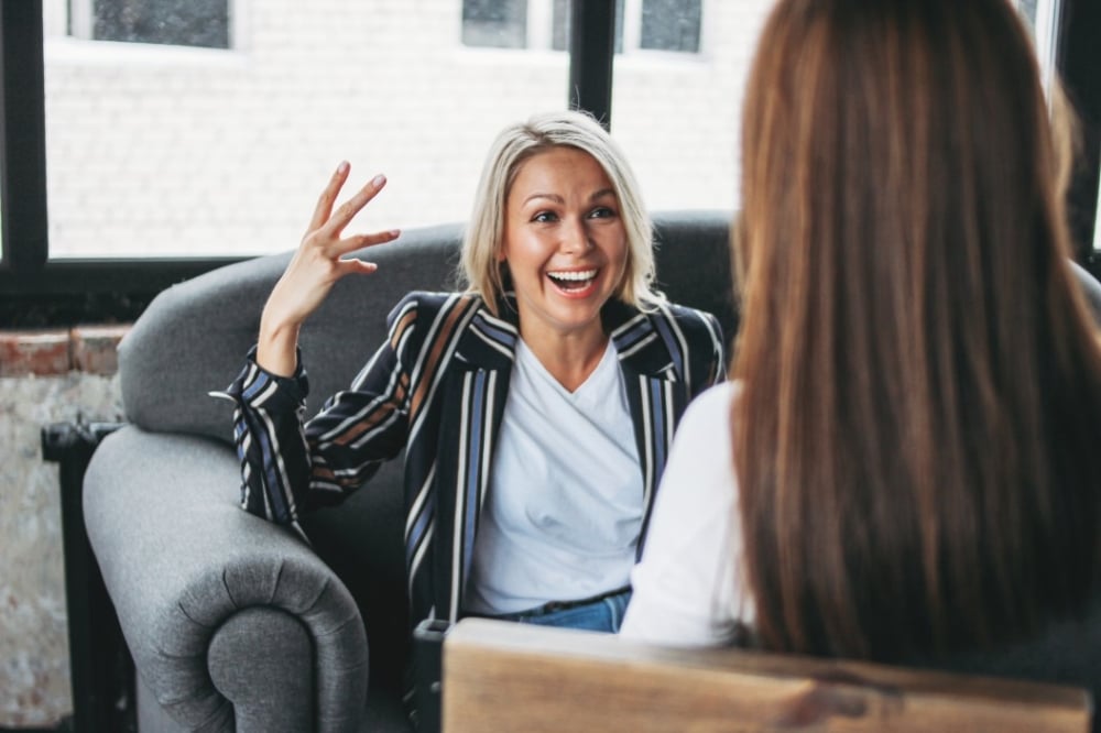 Women engaged in a friendly conversation, discussing relationship-building in a professional setting, emphasizing trust and effective communication.