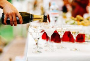 Champagne being poured into elegant glasses at a festive event, highlighting celebration and catering for weddings and parties.