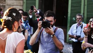 Photographer capturing a moment at a lively event surrounded by guests, with bubbles floating in the air, emphasizing engagement and celebration at corporate events or private parties.