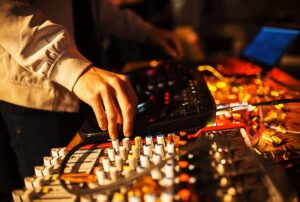 Person adjusting sound equipment and mixer at an event, enhancing party atmosphere for celebrations.