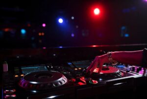 DJ mixing music at an event, with colorful stage lights and sound equipment, enhancing the atmosphere for guest engagement and entertainment.