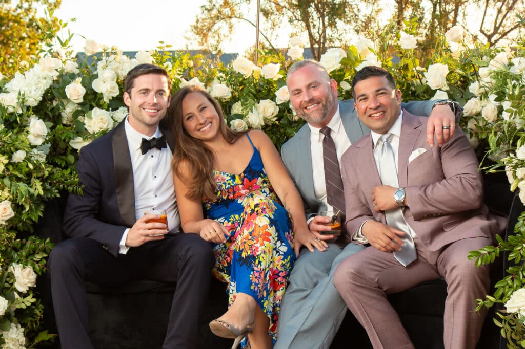 Wedding portrait with guests in 360 booth and floral backdrop