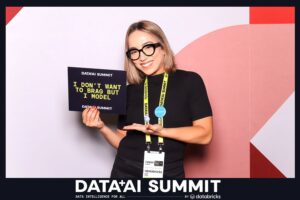Woman holding a sign that reads "I DON'T WANT TO BRAG BUT I MODEL" at the Data + AI Summit, showcasing the interactive experience of Pop Life Photo Booth with custom props.