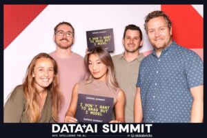 Group of five attendees at the Data + AI Summit holding custom props with playful text, showcasing engagement and networking at the corporate event.