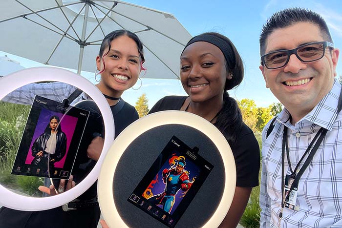 Alyssa and Kamilah holding digital displays featuring vibrant images, showcasing the interactive AI Roaming Booth at Intuit's event.