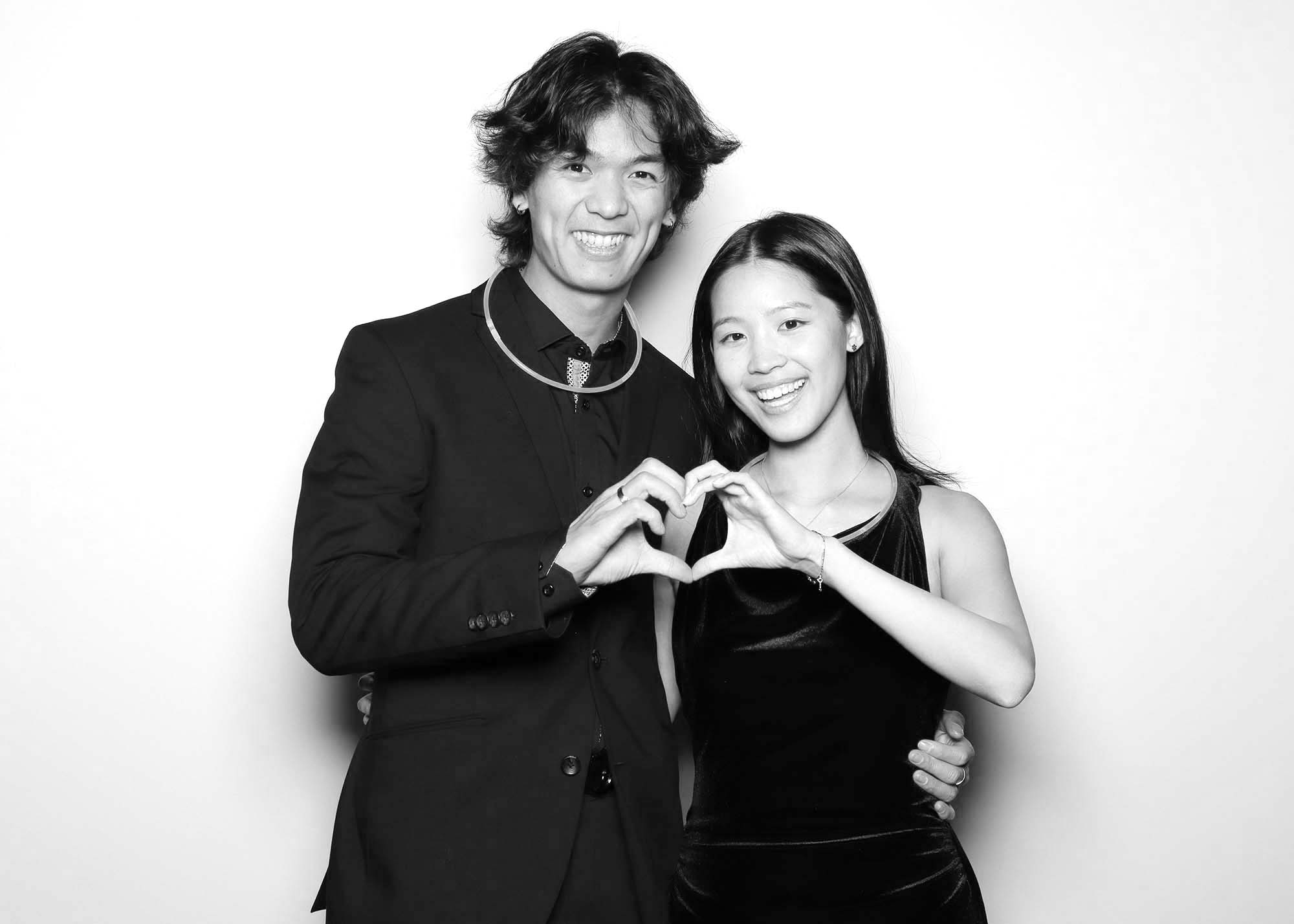 Couple posing together in a photo booth, making a heart shape with their hands, showcasing love and connection, ideal for capturing memorable moments at events.