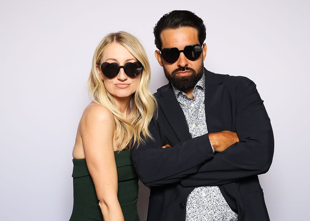 Couple posing seriously with sunglasses, embodying a chic and confident vibe, perfect for trendy photo booth moments.