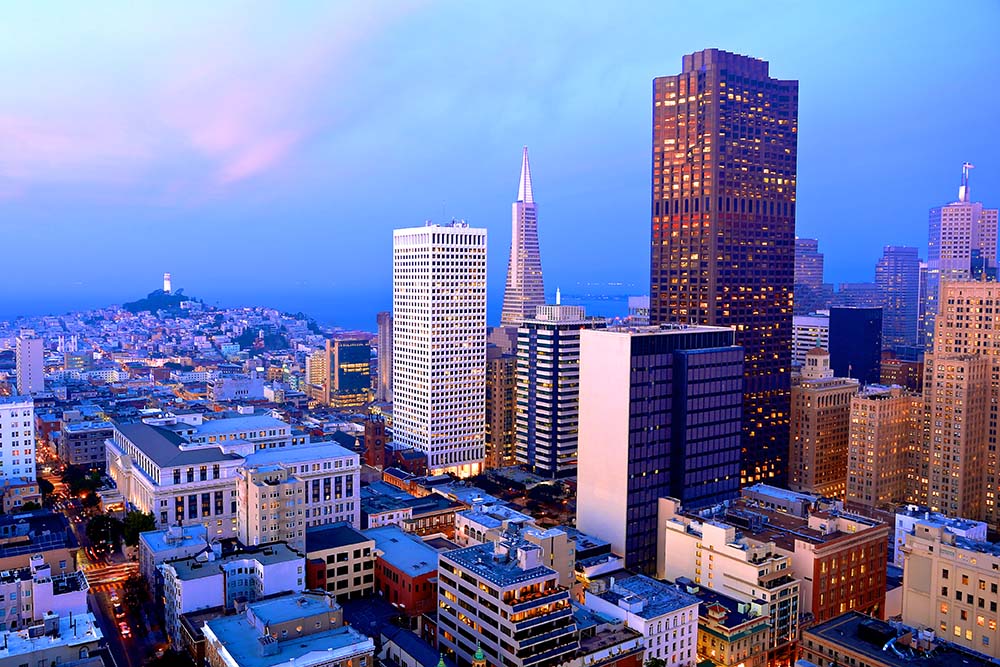 San Francisco skyline at dusk, featuring iconic buildings like the Transamerica Pyramid and Coit Tower, showcasing the vibrant urban landscape surrounding Hotel Nikko, a premier event venue.