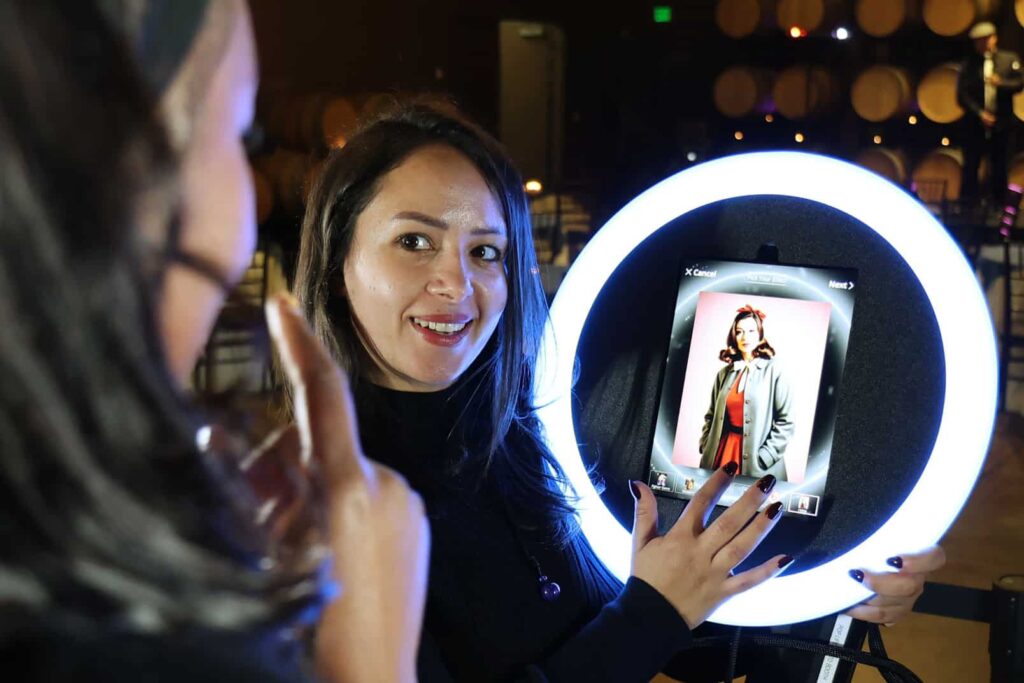 Woman interacting with a roaming AI photo booth, showcasing an AI-enhanced image on a tablet within a glowing ring light, capturing spontaneous event moments.