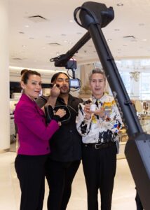 Three individuals engaging with a Glambot photo booth, showcasing a stylish setup with professional lighting, in a corporate event setting.