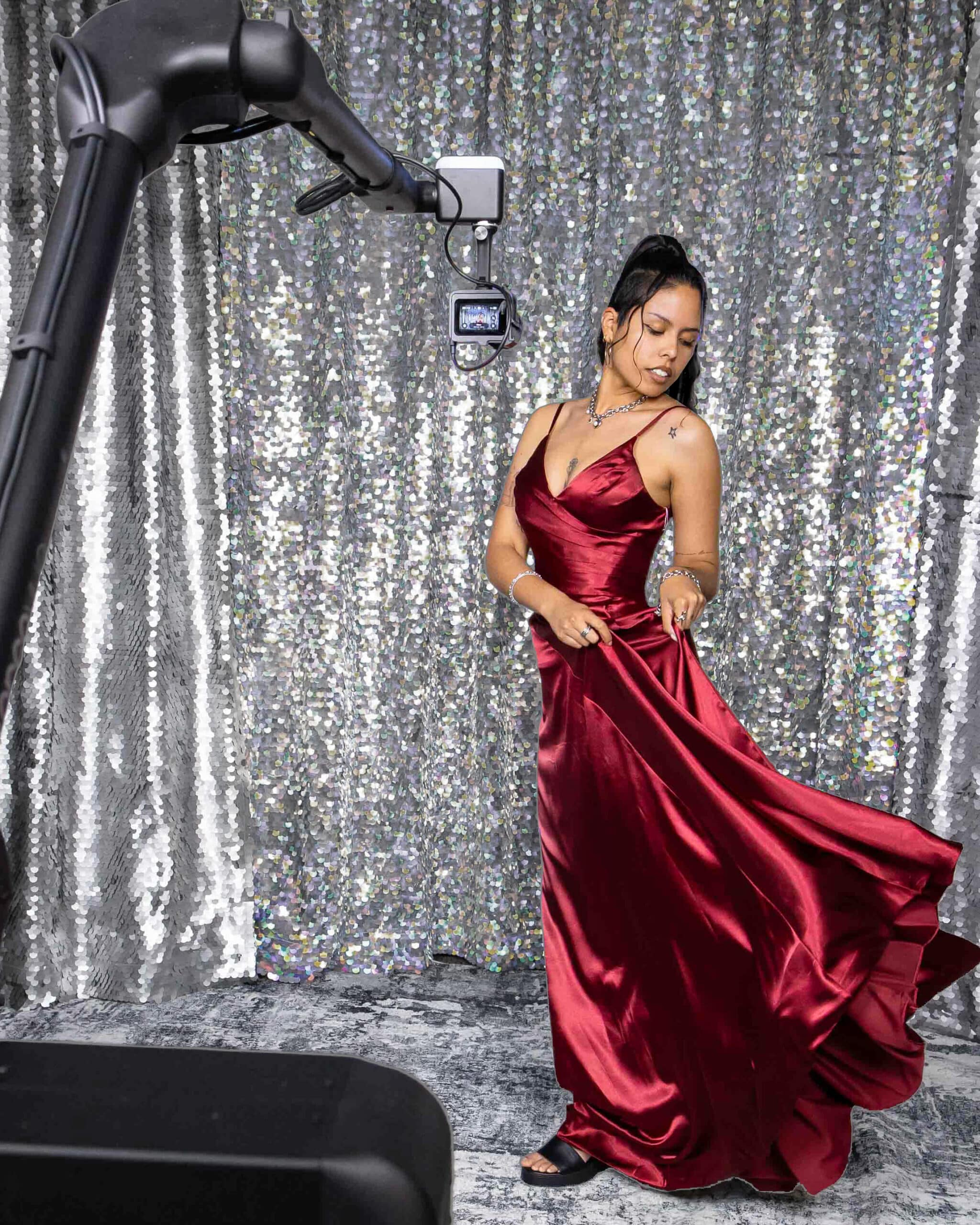 Glambot robotic arm capturing slow-motion video of woman in red dress at event.