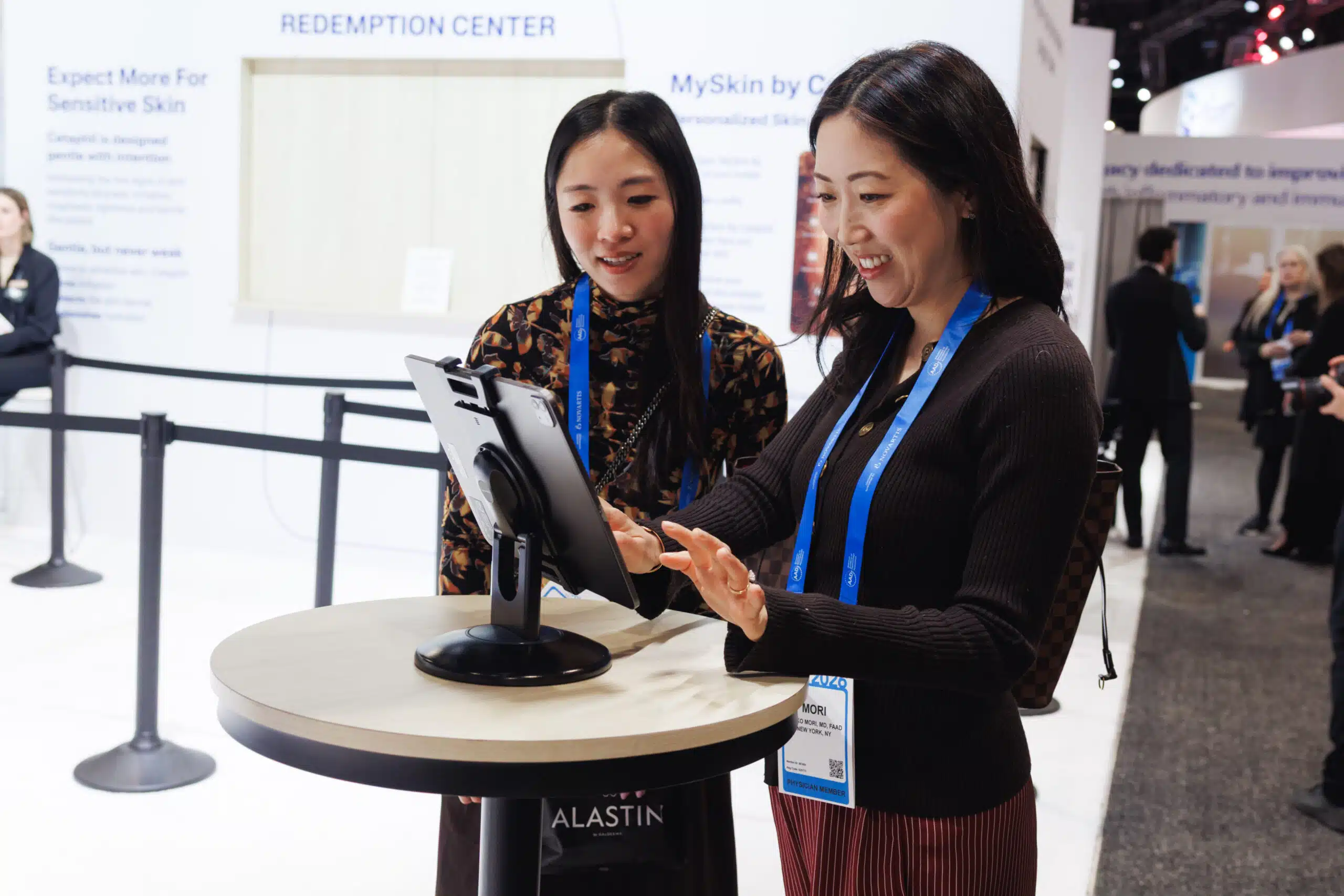 Two women interacting with a Pop Life Photo booth at the American Academy of Dermatology Annual Meeting, showcasing a premium brand moment for Galderma.