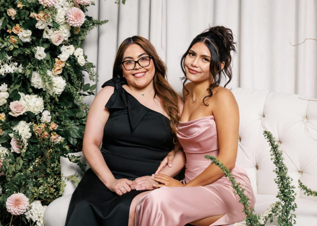 Portrait photography of two women in formal dresses, floral backdrop and seating for Pop Life Photo experiences.