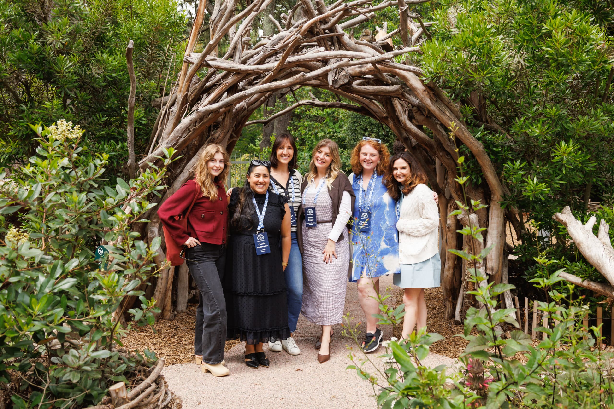 Group of smiling guests and Pop Life Photo team members captured in a natural archway, editorial event photography.