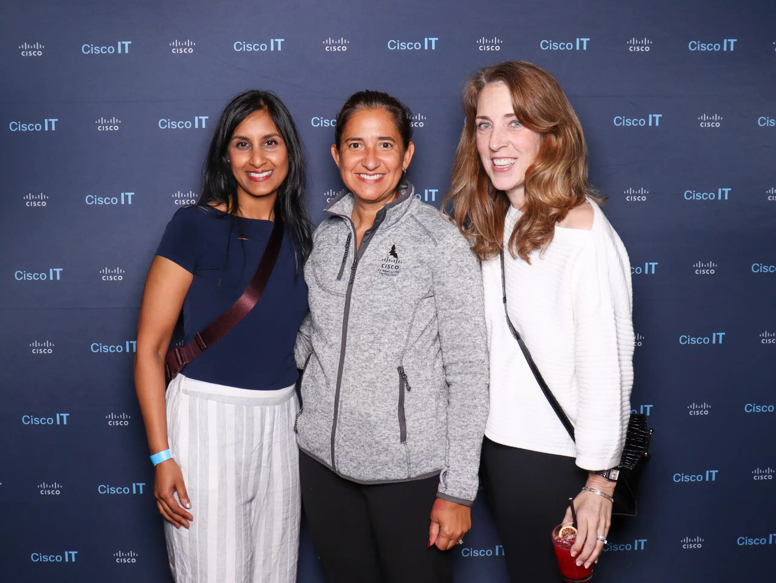 Branded Cisco IT photo booth with three smiling guests and custom backdrop.
