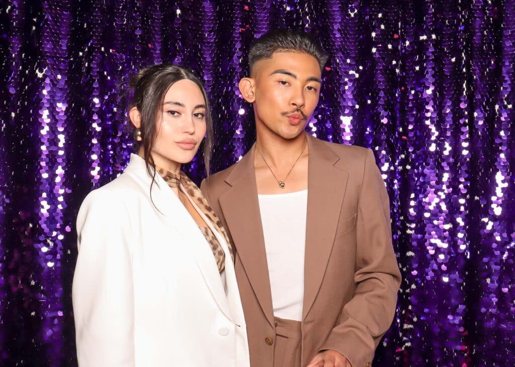 Couple posing in front of a shimmering purple sequin backdrop, ideal for glamorous photo booth settings at upscale events.
