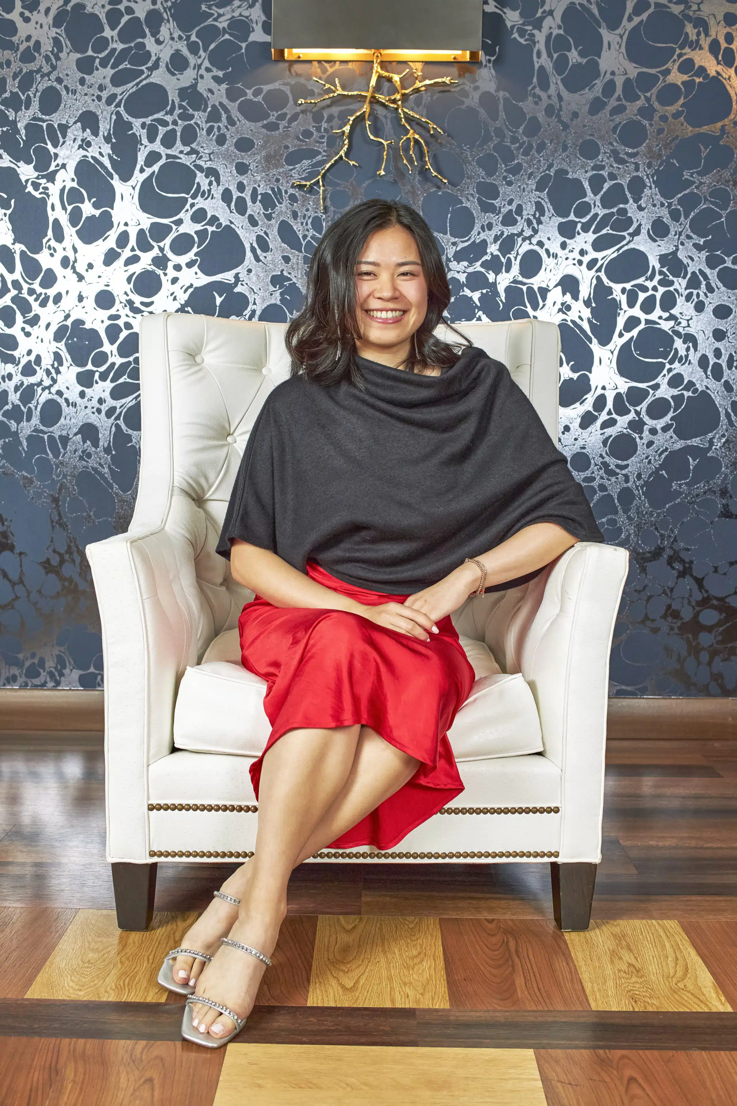 Woman seated in armchair, editorial-style portrait photography experience, custom branded event.
