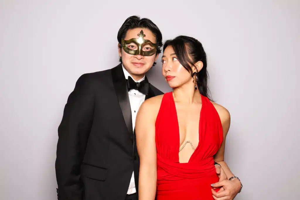 Couple posing in formal wear and masks at a corporate holiday celebration, Pop Life Photo booth experience.